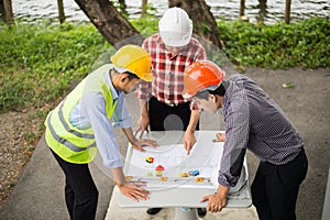 Engineer and construction team wearing safety helmet and looking blueprint on the table at construction site.