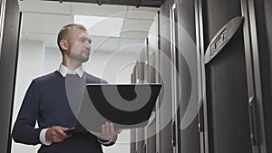 IT engineer control server room of datacenter holding laptop