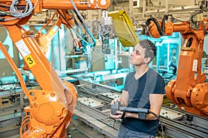 Engineer controls using remote control of industrial robot in factory. Automatic welding and gluing using automation and