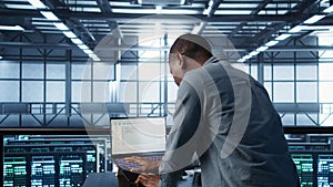 Engineer in data center coding on laptop, optimizing resource utilization