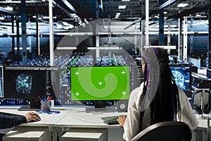 Engineer in data center using green screen PC, optimizing hardware for AI tasks