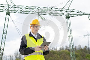 Engineer with digital tablet on a background of power line tower