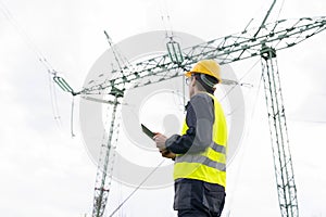Engineer with digital tablet on a background of power line tower
