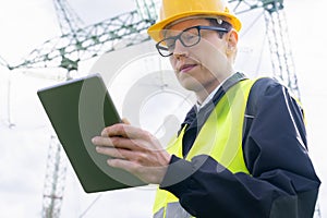 Engineer with digital tablet on a background of power line tower