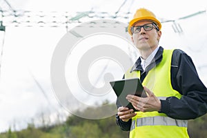 Engineer with digital tablet on a background of power line tower