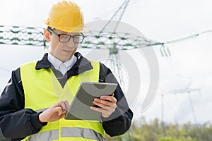 Engineer with digital tablet on a background of power line tower