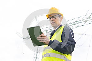 Engineer with digital tablet on a background of power line tower