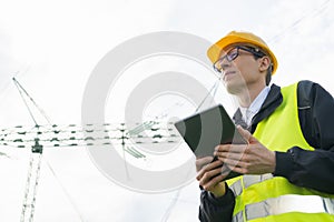 Engineer with digital tablet on a background of power line tower