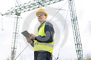 Engineer with digital tablet on a background of power line tower