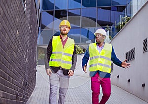 Engineer discussing the structure of the building with architects colleague at construction site. Businessmen talking