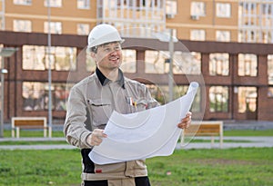 Engineer with a drawing in his hands, smiling, looking at the new building