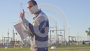 Engineer at Electrical Substation. Worker with blueprints and clipboard in meeting at electrical substation.