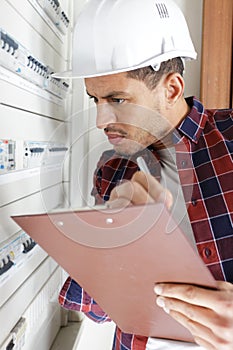 engineer electrician with clipboard in electrical control box