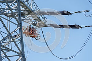 Engineer Electrician Workers On Lift Repairing Electricity Pylon Powerline