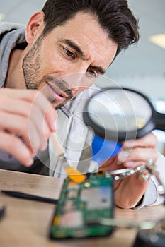 Engineer examining computer circuitry though magnifier