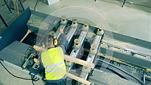 Engineer is examining wooden balks processed by the machine