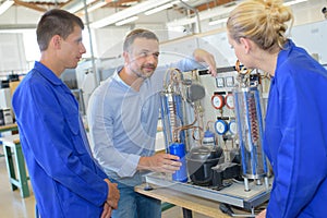 Engineer in factory with apprentices checking components