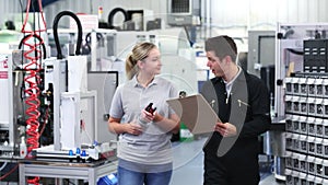 Engineer in factory discussing component with female apprentice