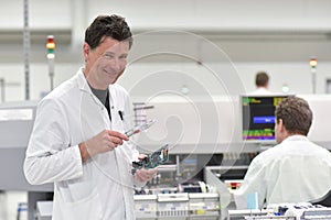 engineer in a factory for the production of electronic components checks the quality of an assembled board with the help of a