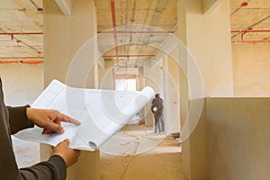Engineer finger point on paper plan blueprint in check building technician place construction site wall interior with copy space