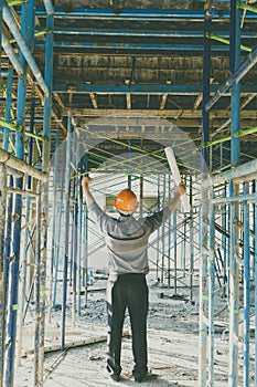 Engineer or foreman with blueprint in building construction site.