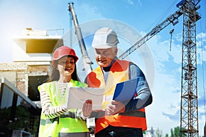 Engineer and foreman in safety equipment with tablet at construction site