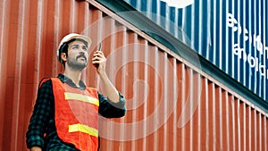 Engineer or foreman use walkie-talkie to work. In order to move container and shipping. Safety helmet help prevent accident from