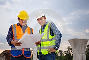 Engineer and foreman worker checking project at building site, Engineer and builders in hardhats discussing blueprint on