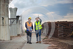 Engineer and foreman worker checking project at building site, Engineer and builders in hardhats discussing blueprint on