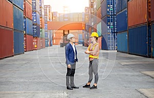 Engineer and foreman worker team in hardhat and safety vest control loading containers box from cargo