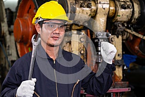 Engineer or foreman worker wearing helmet and safety glasses standing and raise his hand and holding wrench, working at