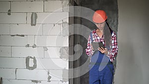 engineer with gadget in building under construction. Modern construction woman engineer or architect in helmet at