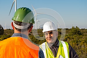 Engineer and geologist consult close to wind turbines in the countryside