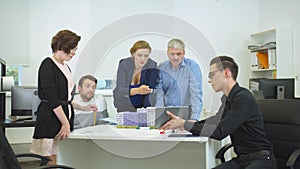 Engineer in glasses show something on tablet to his workmates