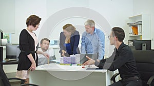 Engineer in glasses show something on tablet to his workmates