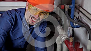 An engineer in glasses works in the boiler room, checks the maintenance of the heating system equipment
