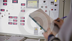 Engineer hands writing information from industrial electronic control board, control panel.