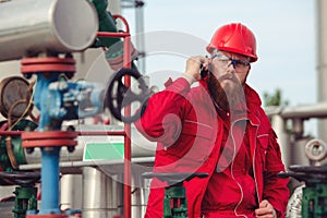 Engineer in hard-hat. Face behind pipeline machinery, fuel and oil refinery.