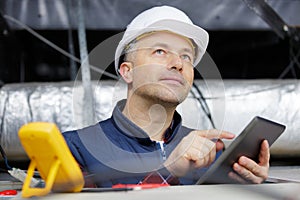 engineer in hardhat using tablet in construction site
