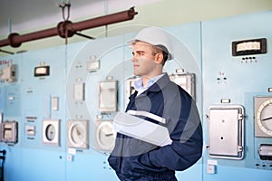 Engineer with helmet and blueprints at control room