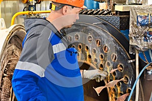 Engineer in helmet inspects and repairs gas equipment of boiler room. Cleaning and maintenance of gas boiler.