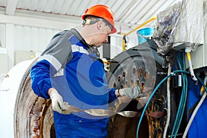 Engineer in helmet inspects and repairs gas equipment of boiler room. Cleaning and maintenance of gas boiler.