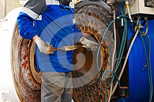 Engineer in helmet inspects and repairs gas equipment of boiler room. Cleaning and maintenance of gas boiler.