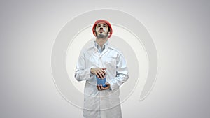 Engineer in helmet and white coat launching demolition on white background.