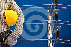 Engineer with high voltage electricity pole in blue sky