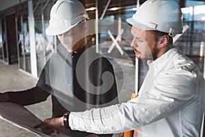 Engineer hold blueprint in hand and discussing project with builder on construction site