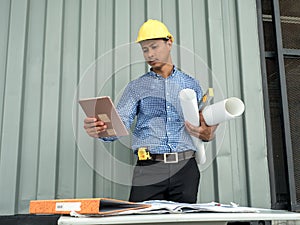 Engineer hold blueprint paper construction drawing plan and holding .tablet, Architect working in office,Engineering tools on desk