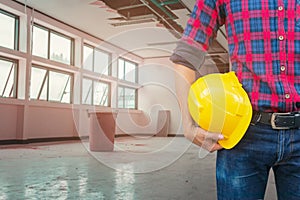 Engineer hold safety helmet inspect in repair leak water pipe under gypsum ceiling interior office building and bucket water