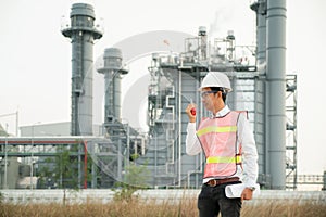 Engineer holding blueprint with radio at power plant. Energy and petrochemical industry