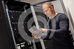 IT Engineer Holding Digital Tablet Analyzing Servers in Datacenter